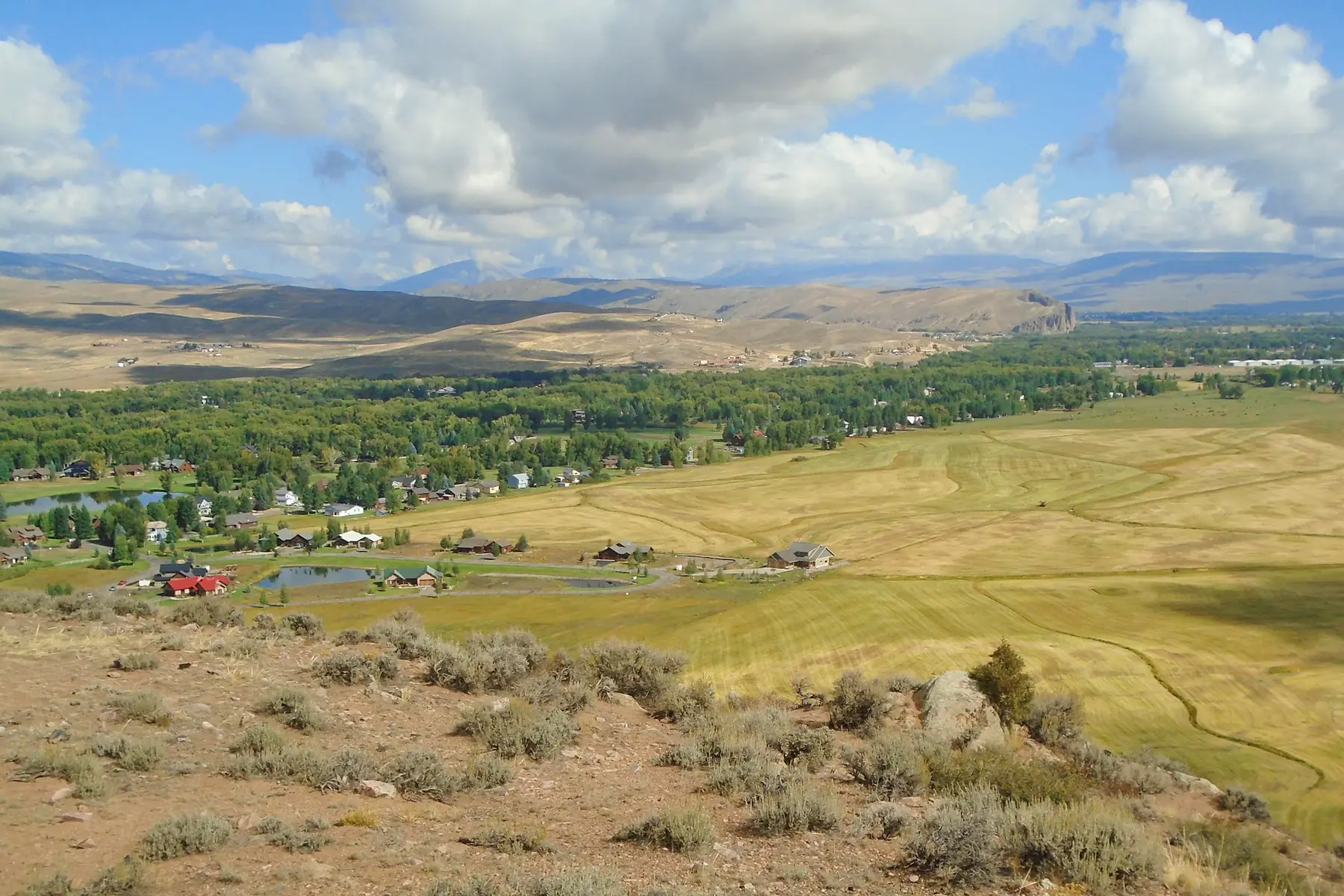 Illustrative Colorado evening scene with homes, a winding road, and mountains
