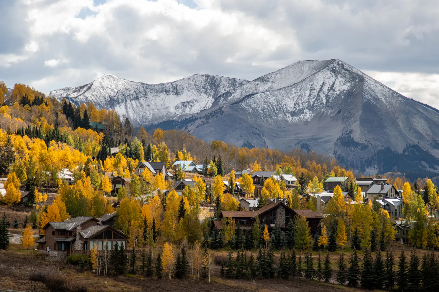 Crested Butte homes among fall aspens with mountains behind